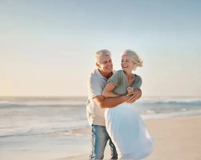 Couple De Senior Heureux se prennant dans les bras sur la plage de Rimouski en été